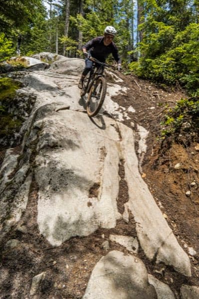 Mountain biker descending a rocky forest trail